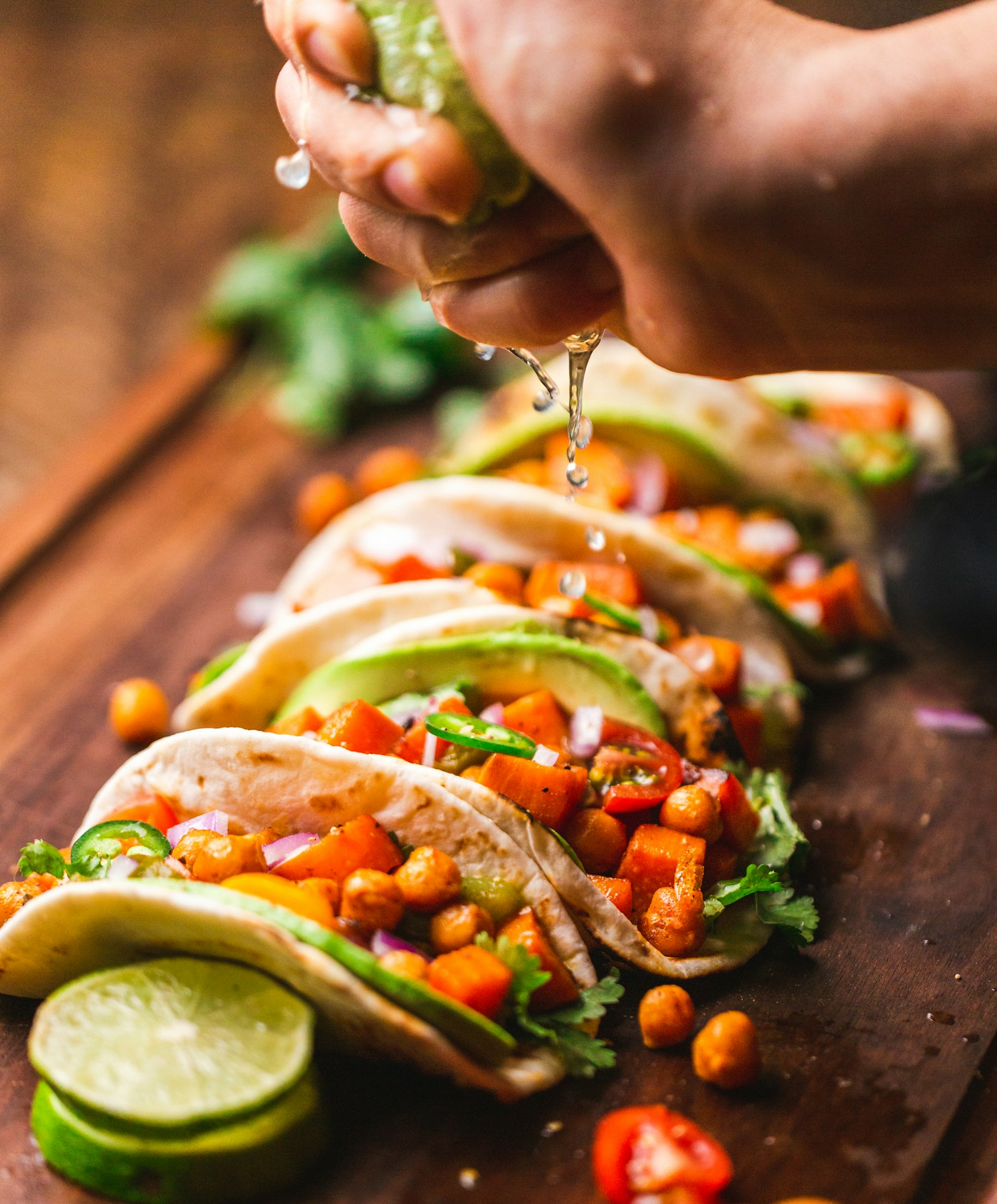 Hænder der samler tacos med friske ingredienser ved en street food-bod